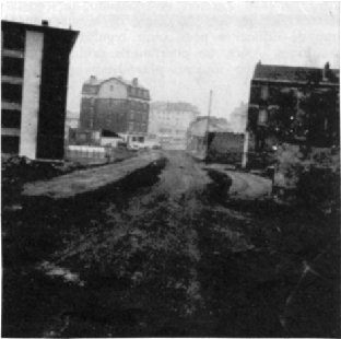 La rue Henri Clérisse, tout juste percée, est encore en terre et va vers le fond de la photo. À gauche, les nouveaux immeubles, à droite, les vieilles maisons en sursis.